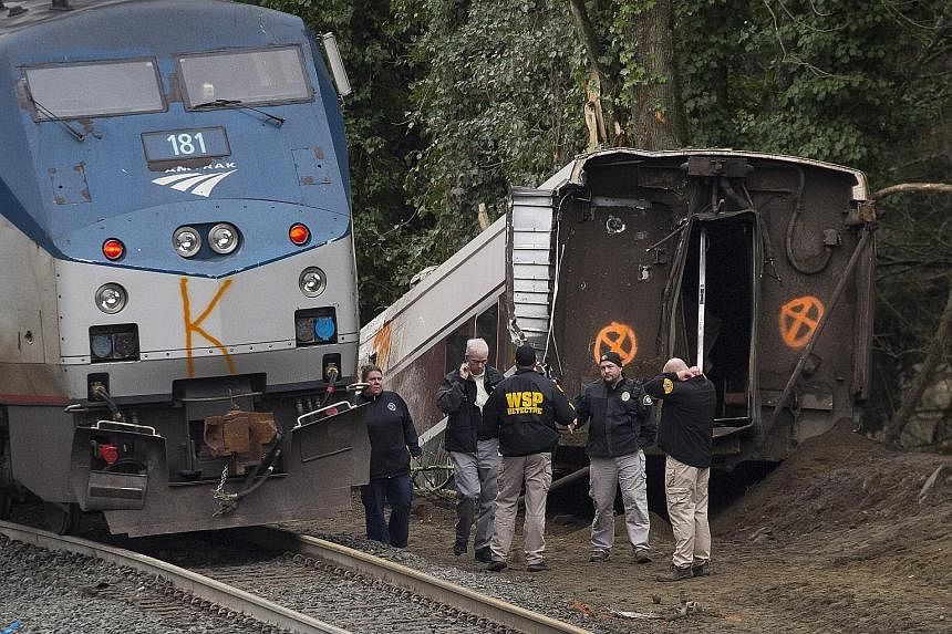 Emergency personnel near the derailed Amtrak train in DuPont, Washington. Thirteen of the train's 14 cars jumped the tracks. The scene at a portion of the Interstate I-5 highway after an Amtrak high-speed train derailed from an overpass on Monday. Th