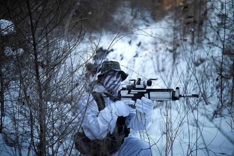 South Korean and United States Marines, in snow camouflage, take part in a winter military drill in the eastern mountainous region of Pyeongchang county, Gangwon, in South Korea yesterday. More than 400 marines from the two allies teamed up for the w