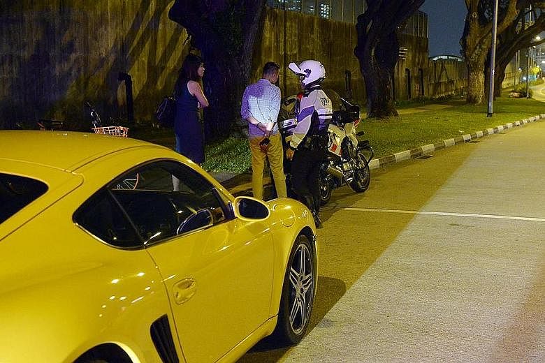A Porsche driver (centre) being checked for drink driving along Kallang Road during an islandwide enforcement operation yesterday. Drink drivers, upon conviction, will lose their driving licences and be disqualified from driving for at least 12 month