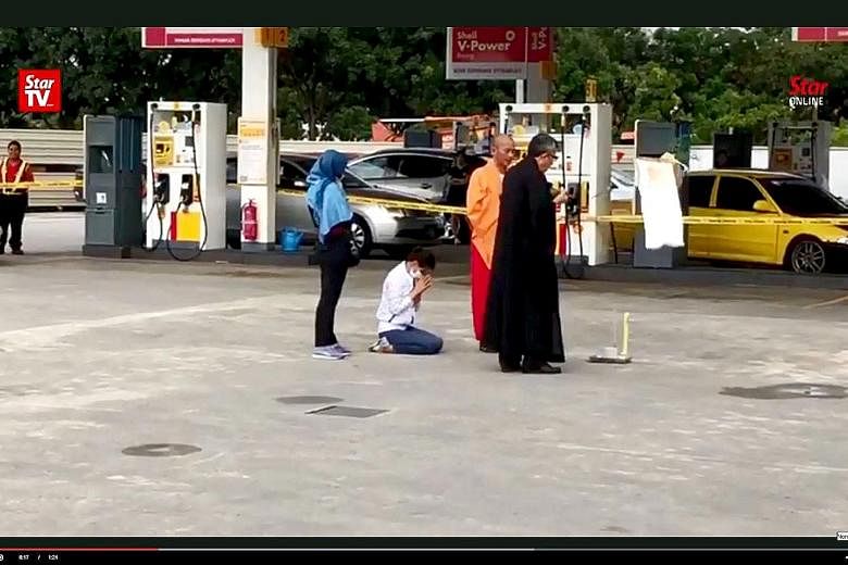 Mr Tan Ah Choy's widow (kneeling) and two Buddhist monks were seen on Tuesday offering prayers at the petrol station in Taman Pelangi, Johor Baru, where the killing took place. Police investigations are going on, including whether the murder was moti