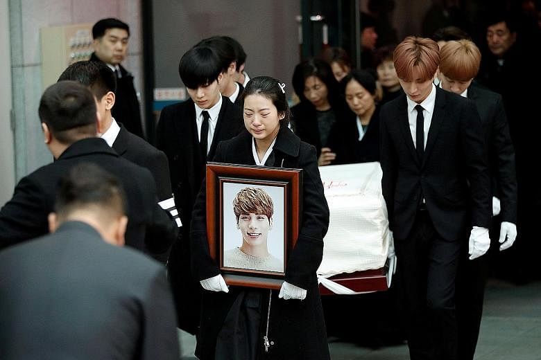 Kim Jong Hyun's SHINee bandmate Minho bearing a plaque topped with a cross and reading "Kim Jong Hyun, believer". Fans of Kim, the lead singer of top South Korean boyband SHINee, weep as a hearse carrying his coffin passes by. Kim's sister, tears cou