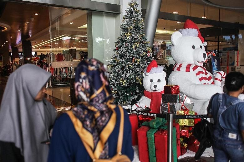Indonesian shoppers at a mall in Medan, North Sumatra Province, yesterday. The hardline Islamic Defenders Front has said it would conduct "sweeping operations" against businesses forcing Muslim staff to wear Christmas attire.