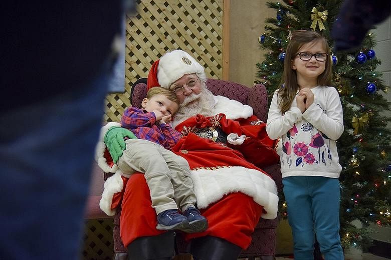 A Santa with pre-schoolers Wyatt Padden, two, and Claire Padden, five, at Cloverdale School in the United States.