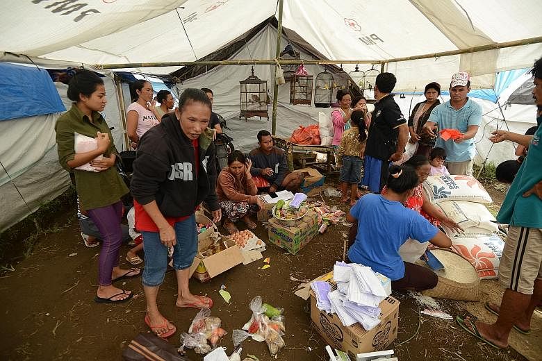 Right: A banner map put up to show the danger zone around Mount Agung, warning people not to enter it. Far right: Evacuees getting their food rations at a temporary shelter in Karangasem district.