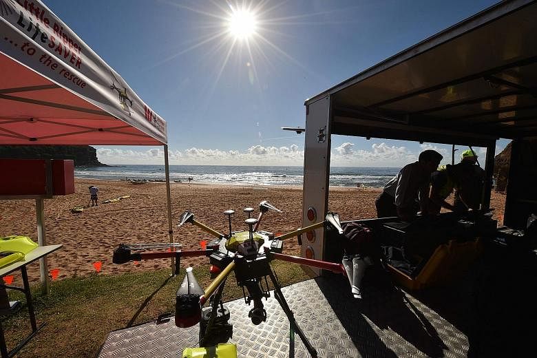 A shark-spotting drone (above), at Bigola beach north of Sydney, which is able to obtain aerial images of sharks in the water (below) and alert beachgoers to danger.