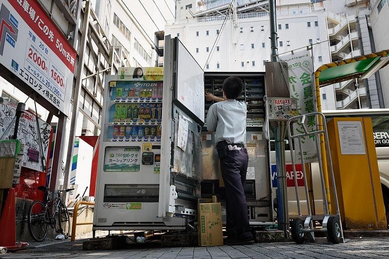 A worker filling up a vending machine. Japan's November retail sales, including food and beverage, rose 2.2 per cent from a year ago.