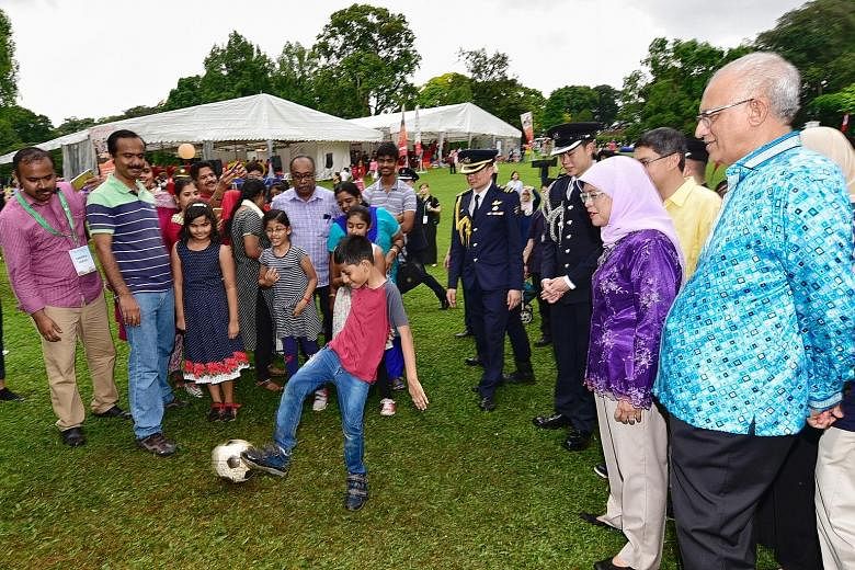 President Halimah Yacob and her husband, Mr Mohamed Abdullah Alhabshee, observing eight-year-old Adhavan Senthil Kumar kicking a football while his family members look on. The Jayabalan family - all 17 of them - was among the crowd at the Families fo