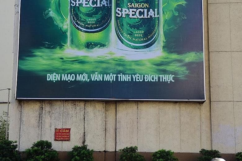 People ride past beer advertising outside Sabeco's main brewery in Ho Chi Minh City. Thai Bev acquired a 53.6 per cent stake in Vietnam's largest state-owned brewer last month.