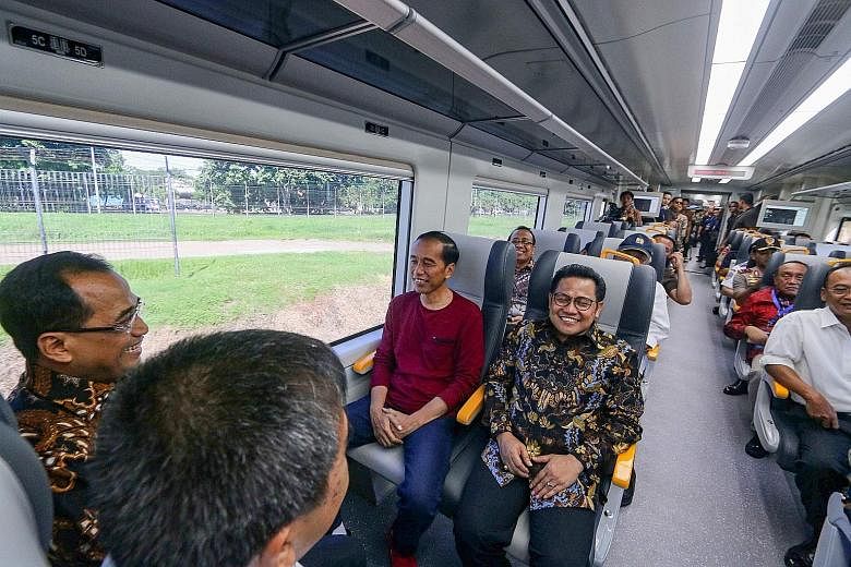 Indonesian President Joko Widodo (in purple T-shirt) taking a ride on the newly launched airport train linking Soekarno-Hatta International Airport to the Jakarta city centre yesterday. The train connection comes as the sprawling Indonesian capital m