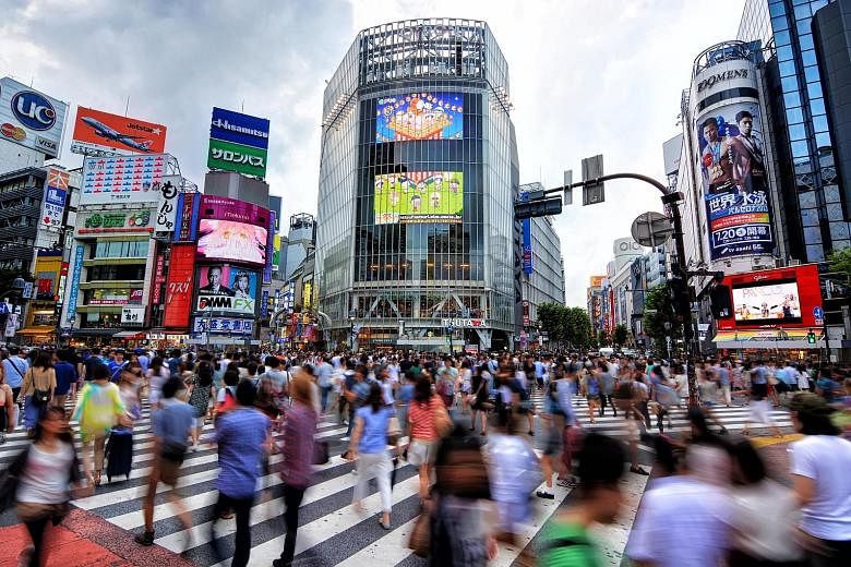 Pedestrians at Tokyo's famous Shibuya scramble crossing. It began in 1973 and is now the world's busiest with more than 3,000 people crossing at a go during rush hour.