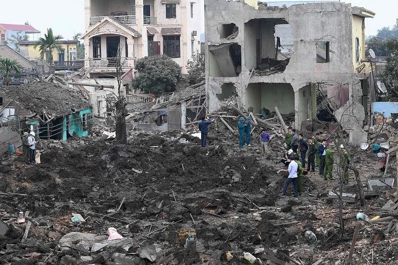 Soldiers and rescuers at the site of the explosion in Ban Ninh province's Yen Phong district yesterday. The early morning blast reduced four homes to rubble and shattered the windows of surrounding buildings. Many families in the area are involved in