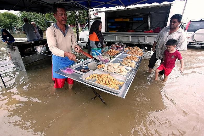 A food seller in Sungai Isap Damai Park in Kuantan continuing to work yesterday despite the flooding. The floods had forced 11 schools in Pahang to remain closed on Tuesday on the first day of the new school year.