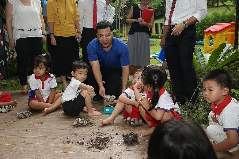 Minister for Social and Family Development Desmond Lee spending some time with children learning gardening during a visit to PCF Sparkletots @ Marsiling on Tuesday.
