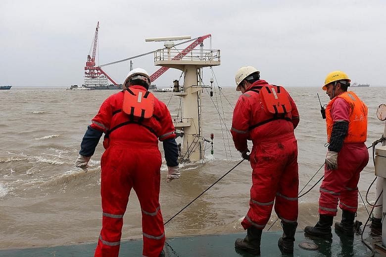 Workers on a rescue ship at the site where cargo vessel Changping, loaded with 5,000 tonnes of steel, collided with another freighter and sank at Wusongkou anchorage near the Yangtze estuary in Shanghai yesterday. Three people have been rescued while