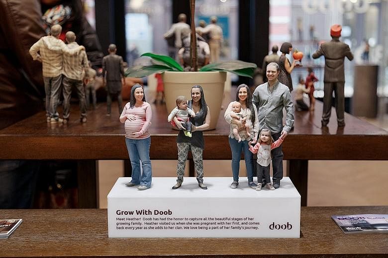 Figurines of a woman when pregnant and with her children and husband (above) at a Doob store in New York. Custom cake-maker Ashley Holt (right) with a doob of herself posing mouth wide open in midbite.