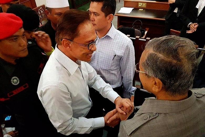 Former Malaysian prime minister Mahathir Mohamad clasping hands with Anwar Ibrahim at the Kuala Lumpur High Court on Sept 5, 2016, at the hearing of an application filed by his jailed ex-deputy.
