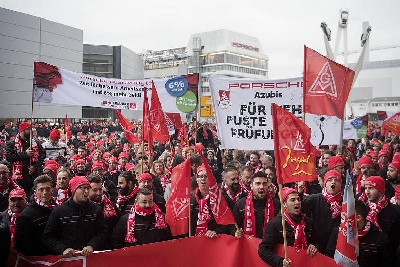 Employees of automobile company Porsche demonstrating yesterday in front of their plant in Stuttgart, southern Germany, with flags showing the logo of Germany's metalworkers' union, IG Metall. The powerful union has called for a series of strikes ove