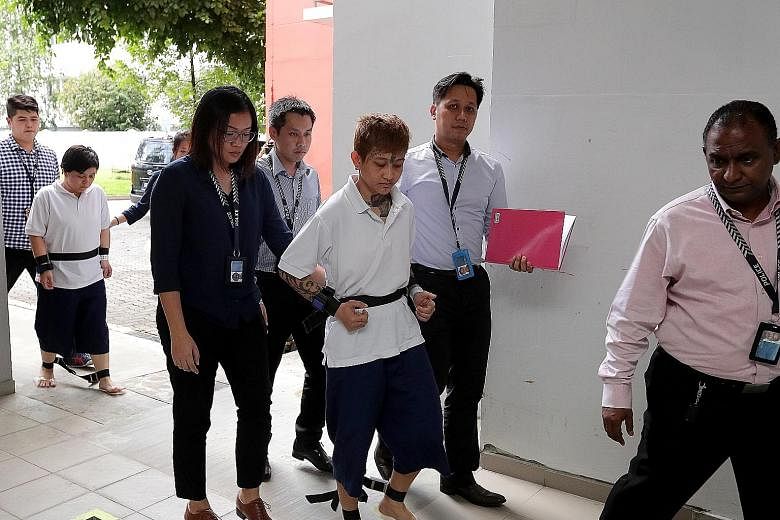 Raslindawati Abdul Rashid (centre) and Joanna Michell Tan Jiamei with police officers at the crime scene at Block 271B in Sengkang Central yesterday. The two women are suspected of setting fire to the entrance of a flat in the block.