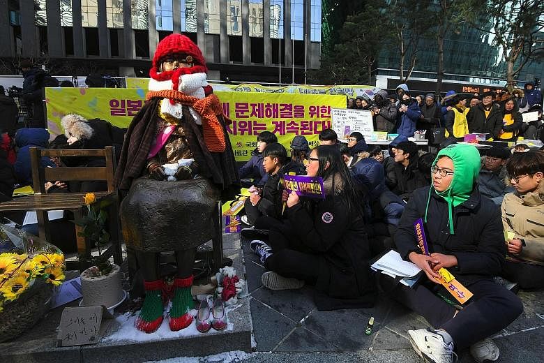Protesters beside a comfort woman statue at a rally near the Japanese Embassy in Seoul yesterday. In his national address, South Korean President Moon Jae In said the 2015 comfort women accord with Japan was undeniable, but the issue can be resolved 