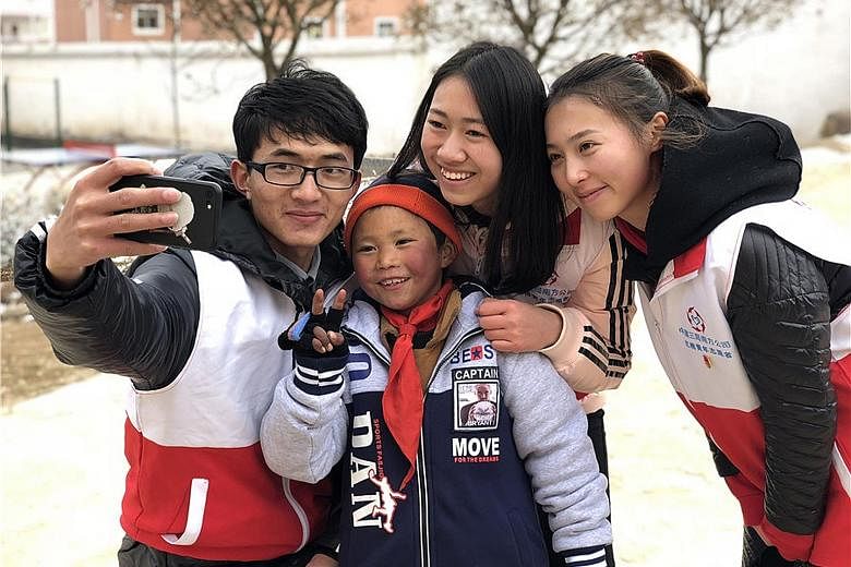 Volunteers with eight-year-old Wang Fuman after helping him put on a pair of gloves. Donations, including winter clothing and heaters for his school in Yunnan, have poured in since his "Snowflake Boy" photo went viral.