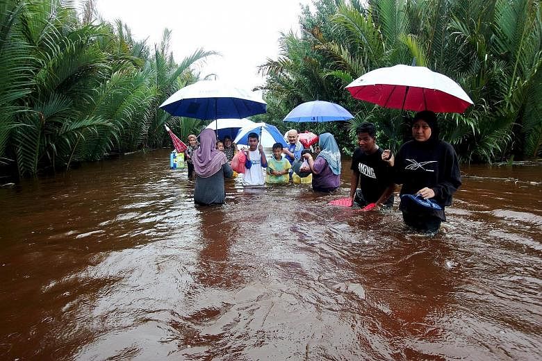 Villagers from Kampung Palong in Pekan district, Pahang, wading through flood waters yesterday to get to the main road. The road in an oil palm estate has been flooded for the past three days.
