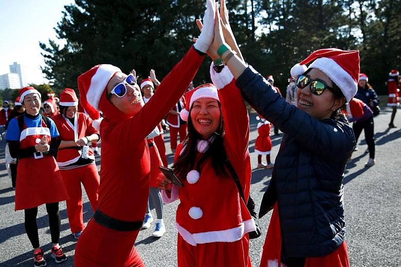 Participants dressed up as Santa Claus do a high-five at an annual charity run event in Chiba, Japan, last month.