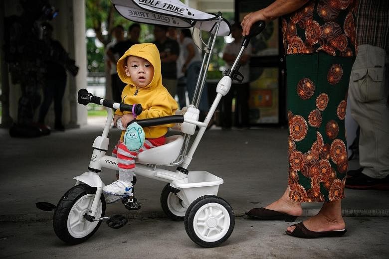 A little boy warmly dressed while taking a ride in Bukit Batok Street 51 yesterday. The thermometer reading dipped to 21.2 deg C in Admiralty and Jurong West at around 5am yesterday morning.