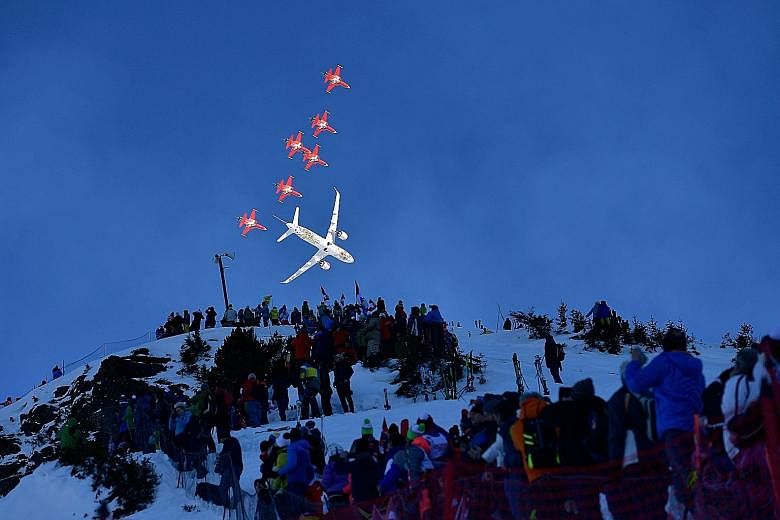 Fighter jets of the Patrouille Suisse, the aerobatic team of the Swiss Air Force, and a commercial plane flying over the ski slopes of Wengen, Switzerland, in an aerial display ahead of the men's downhill race at the FIS Alpine Skiing World Cup last 