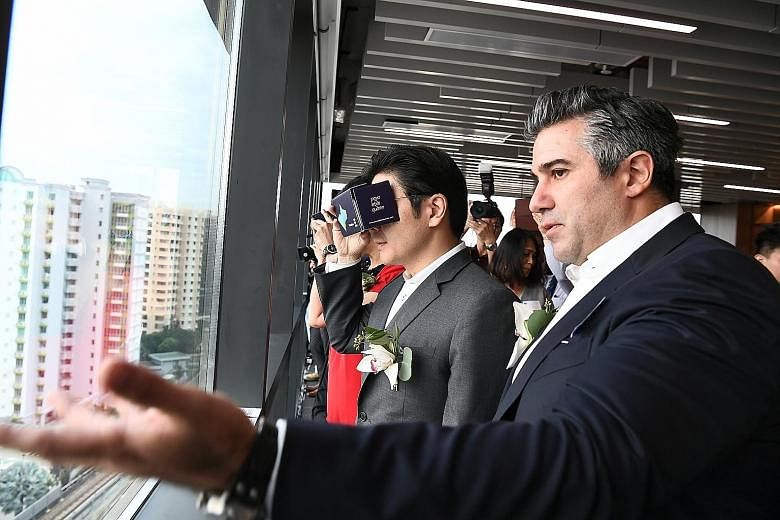 National Development Minister Lawrence Wong and Lendlease Asia chief executive Tony Lombardo at the topping-out ceremony of the first of Paya Lebar Quarter's office towers. Mr Wong is using a virtual reality headset that shows what the development wo