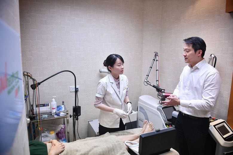 Nurse counsellor Serene Ang explaining to Dr Lam Pin Min the diabetic foot screening using a neurothesiometer being performed on Madam Chng Kah Sing, 57, at Mutual Healthcare Medical Clinic yesterday.