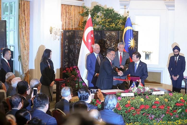 Malaysia's Minister in the Prime Minister's Department Abdul Rahman Dahlan (left) and Singapore's Coordinating Minister for Infrastructure and Minister for Transport Khaw Boon Wan shaking hands yesterday at the Istana after signing a legally binding 