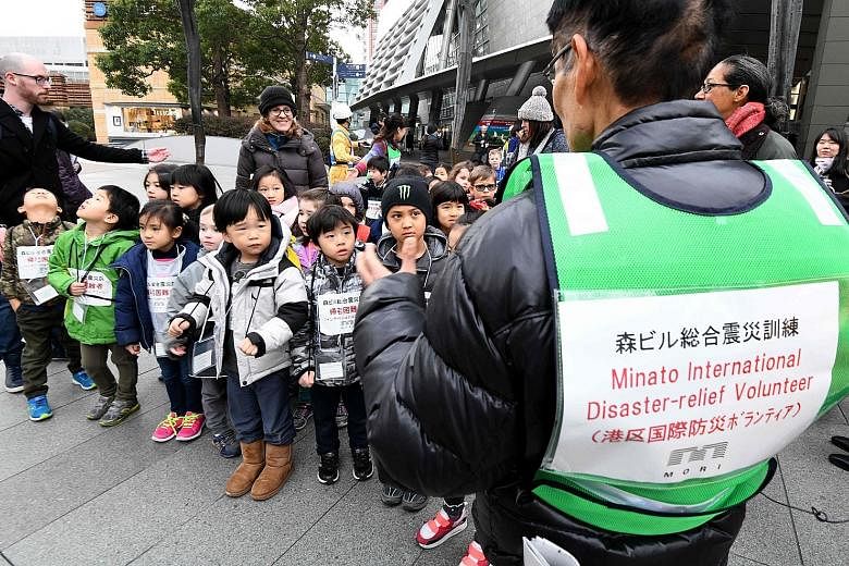 Children from an international school listening to a volunteer interpreter during a disaster drill at the Roppongi Hills business and shopping compound in Tokyo yesterday, the 23rd anniversary of the Great Hanshin Earthquake that killed more than 6,4