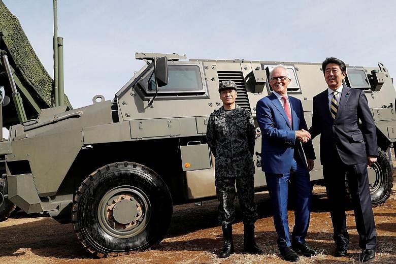Australian Prime Minister Malcolm Turnbull with Japanese Prime Minister Shinzo Abe at the Narashino exercise field in Funabashi, east of Tokyo, yesterday. The two nations will hold a joint military exercise later this year.