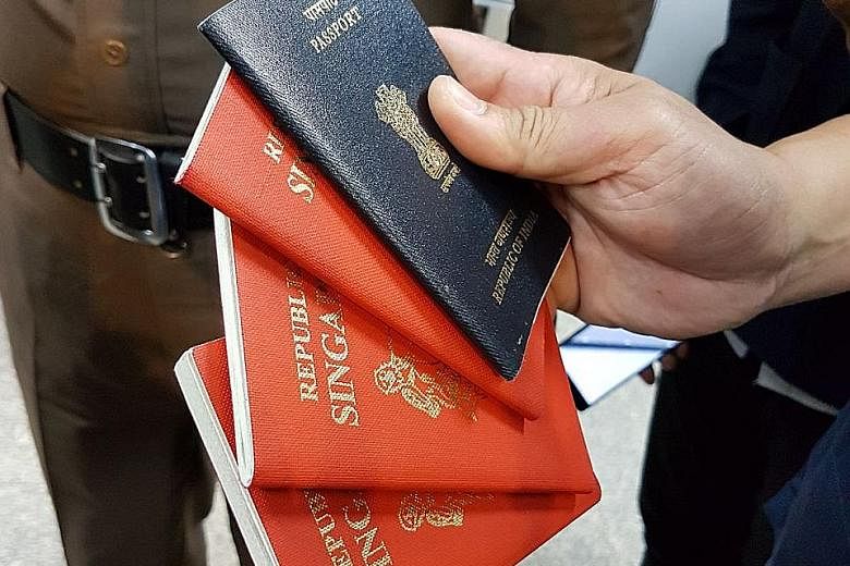 Thai immigration police showing fake Singapore and Indian passports seized from Mohammed Iqbal, who was arrested on Sunday.