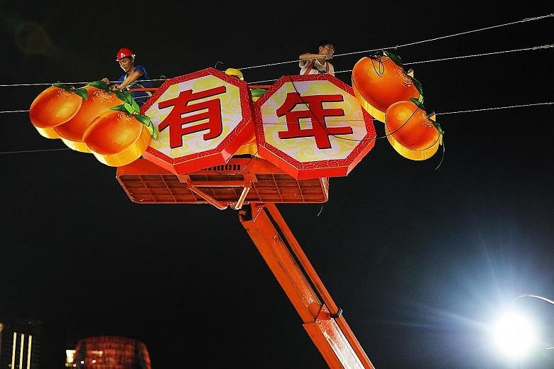 Spring is in the air in tropical Singapore, as workers put up Chinese New Year decorations along South Bridge Road and Temple Street on Tuesday night to welcome the Year of the Dog. 	To ring in the Chinese New Year, the area around Eu Tong Sen Street