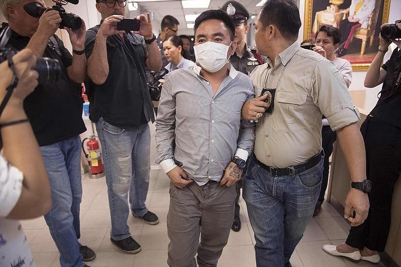 Boonchai Bach being escorted past journalists at a Bangkok police station yesterday.
