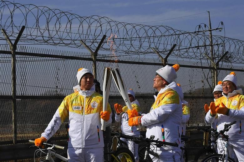 (Left) The Olympic flame is passed on the road to the border truce village of Panmunjom last Friday. (Above) IOC president Thomas Bach flanked by sports ministers Kim Il Guk (left) from North Korea and Do Jong Hwan from South Korea, at the IOC headqu