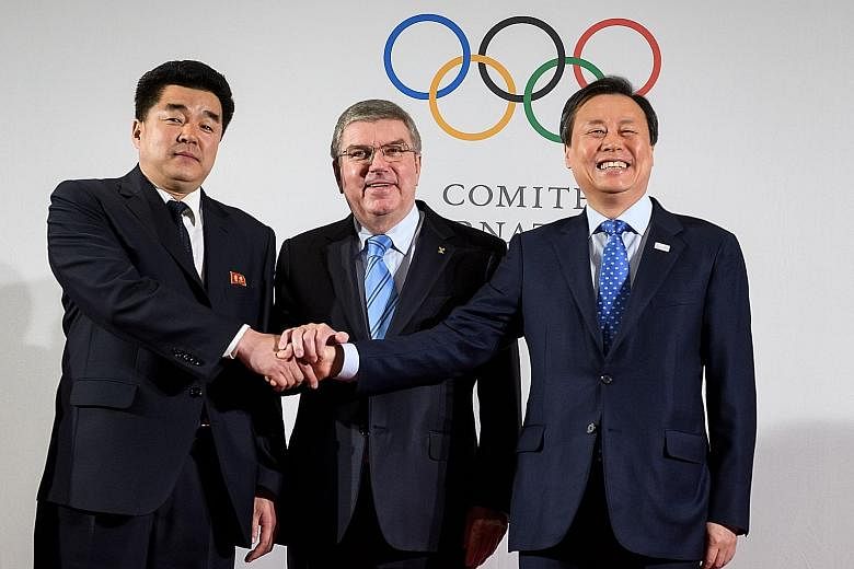 (Left) The Olympic flame is passed on the road to the border truce village of Panmunjom last Friday. (Above) IOC president Thomas Bach flanked by sports ministers Kim Il Guk (left) from North Korea and Do Jong Hwan from South Korea, at the IOC headqu