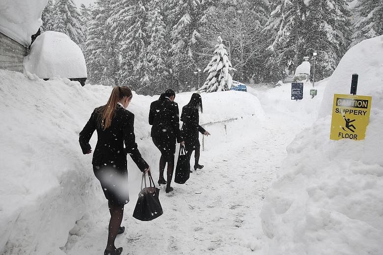 Staff making their way carefully along a path beside the congress centre during heavy snowfall ahead of the World Economic Forum in Davos, Switzerland, yesterday.