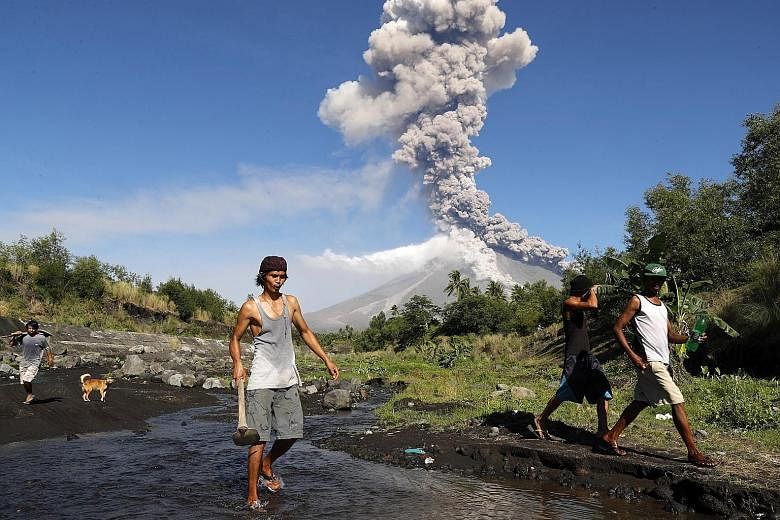Filipino villagers fleeing as Mayon spewed ash and smoke, raining debris on the surrounding areas yesterday.