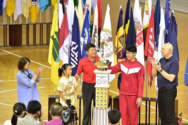 Torch bearer Lincoln Forest Liqht Man, an 18-year-old Singapore Sports School student, lighting the cauldron at the opening of the National School Games yesterday with fellow torch bearer Cassandra Ong, an 11-year-old Tao Nan School pupil. With them 