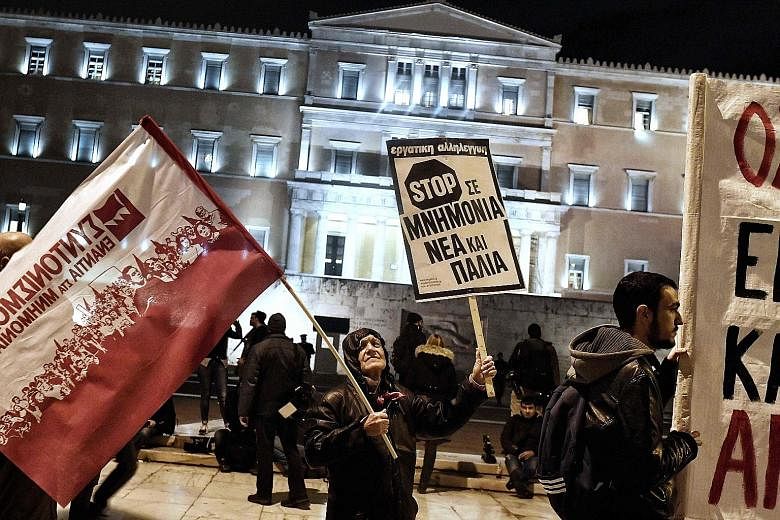 A demonstrator holding a placard reading "stop (bailout) memorandum, old and new" on Jan 15 in front of the Greek Parliament building in Athens in protest against a new round of austerity measures.