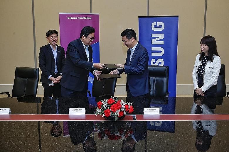 SPH chief executive Ng Yat Chung (second from left) and Samsung Electronics Singapore president Lee Jui Siang exchanging documents after signing a memorandum of understanding yesterday. With them are SPH deputy CEO Anthony Tan and Samsung Electronics