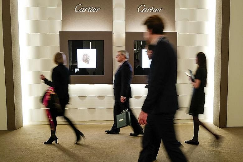 Visitors walking past a Cartier stand, owned by the Richemont group, during the 28th Salon de la Haute Horlogerie in Geneva.