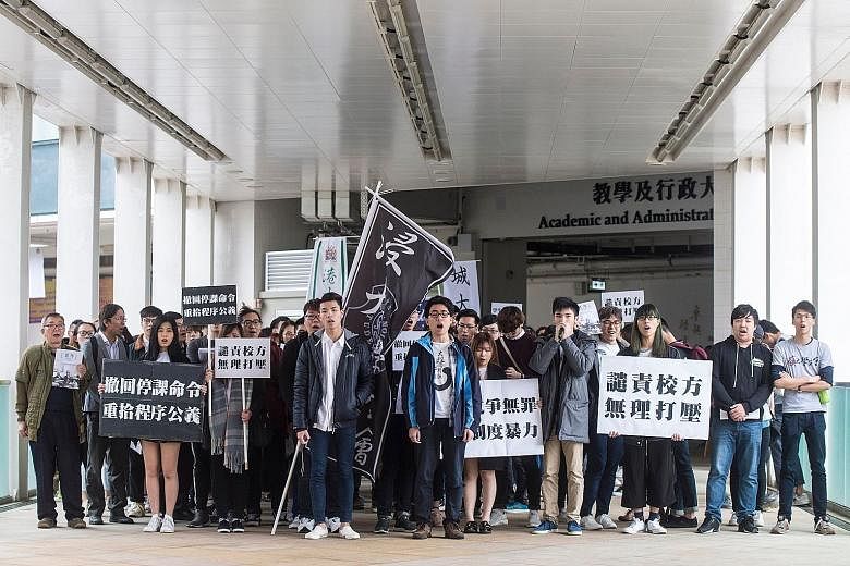 Baptist University students Lau Tsz Kei (centre, left) and Andrew Chan (centre, right) leading demonstrators yesterday in a march against their suspension from school. The duo had been suspended for confronting and swearing at staff over the requirem