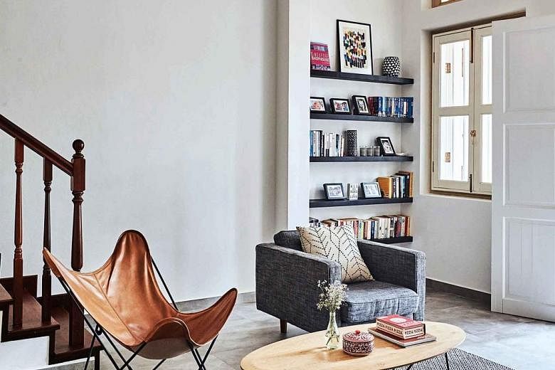 The living room has an open concept. Couple Jonathan Roelandts and Katrien Bollen (with their son, far left) live in a pre-war shophouse, which has a sloping roof on the third floor (left) that lets natural light into the guest room.
