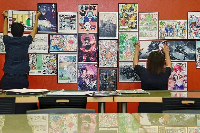 Staff from the Nanyang Academy of Fine Arts putting up artworks for the Singapore Comic Festival.