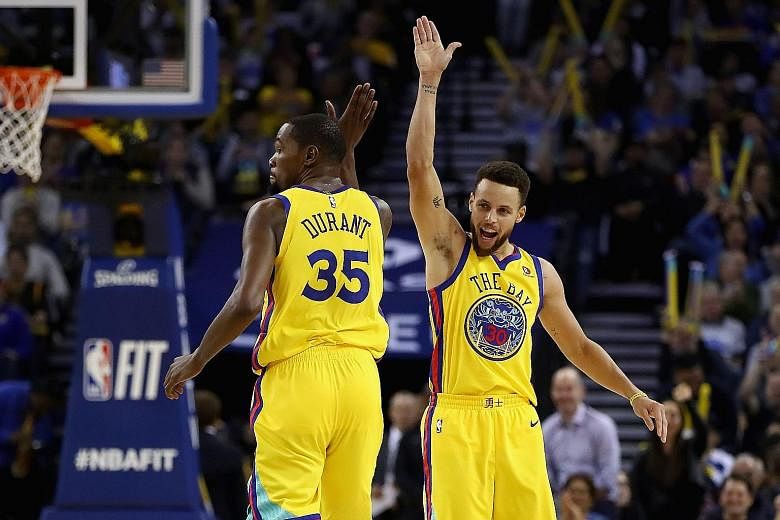 Kevin Durant and Stephen Curry exchanging high-fives on Thursday. The Warriors team-mates will be on opposing sides in the NBA All-Star game on Feb 18 as LeBron James chose Durant with his first pick.