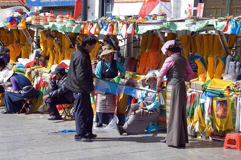 (Above) Vendors selling prayer flags at a Tibetan market in Lhasa. During the Losar new year celebrations, the flags are changed to new and freshly coloured ones. (Left) A man tries to climb a wooden pole to get a prize during the Maslenitsa celebrat