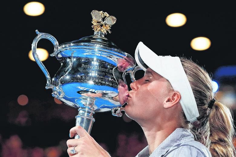 Caroline Wozniacki (top) kissing the trophy after beating Simona Halep 7-6, (7-2), 3-6, 6-4 yesterday to win her first Major at her 43rd attempt - becoming the first Dane to win a Grand Slam singles title; the Romanian Halep (above) receiving medical